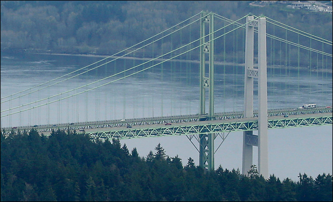 In this March 27, 2013 aerial photo, the control tower and other facilities at the Tacoma Narrows Airport are shown in Gig Harbor, Wash. with the Tacoma Narrows Bridge in the background. The planned closings of control towers at 149 small airports, including the Narrows, due to government-wide spending cuts, are being delayed until mid-June, federal regulators announced Friday, April 5, 2013. (AP Photo/Ted S. Warren)